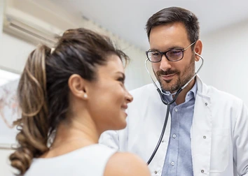 Médico auscultando a una paciente en consulta